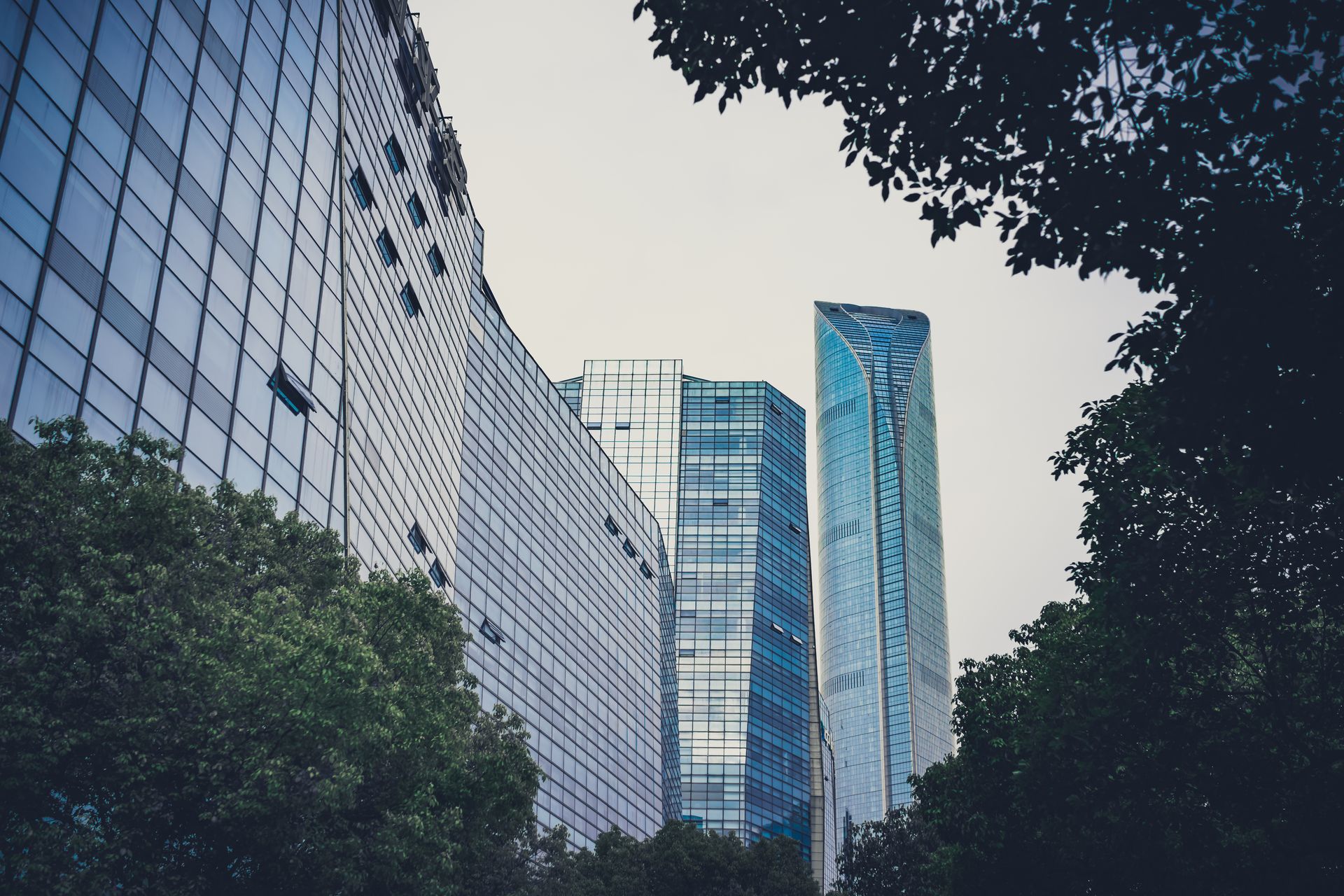 Bürogebäude mit Glasfassade zwischen Bäumen — das ESG-Scoring entscheidet über ihre Finanzierung